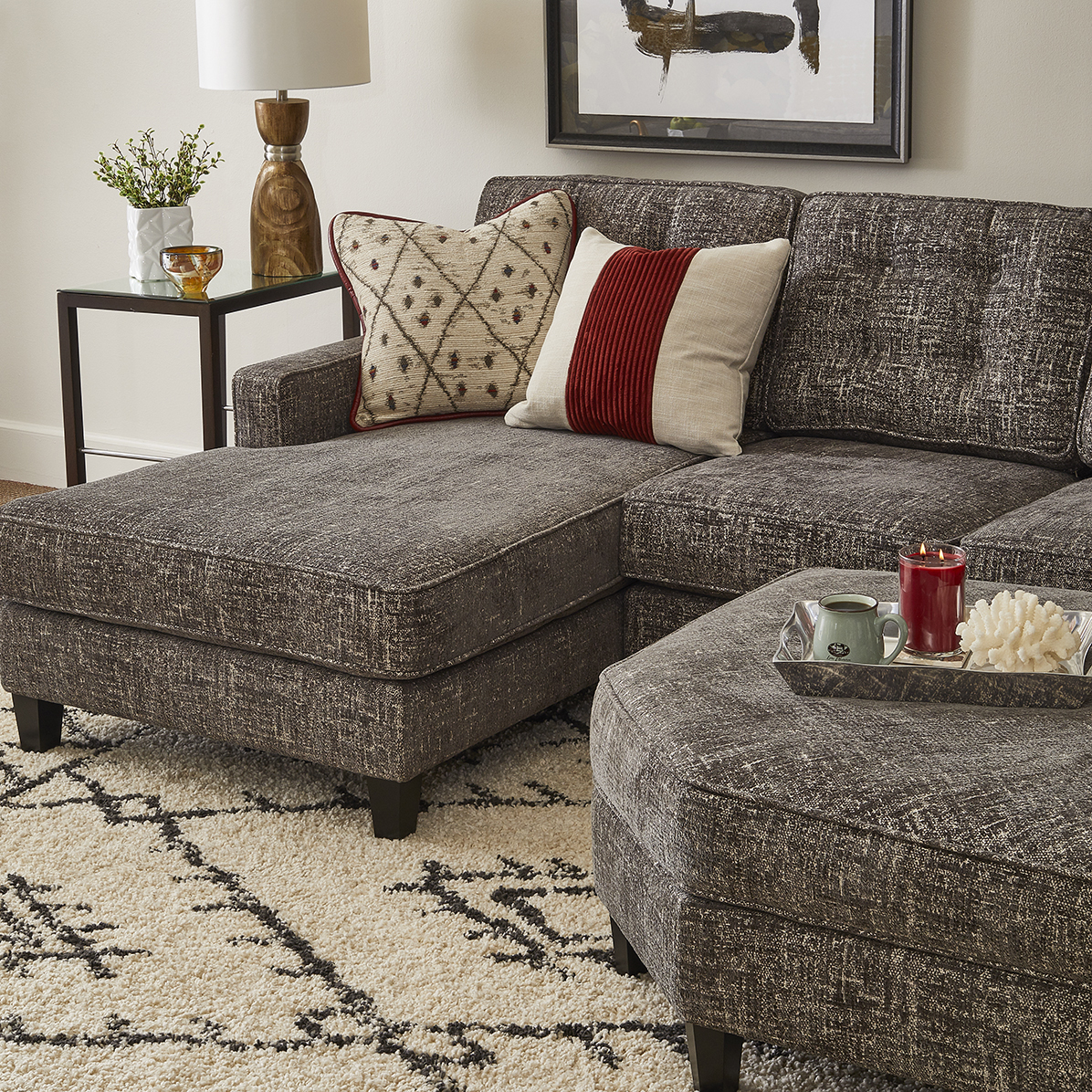 sectional with ottoman and a brown cross-stitch pattern